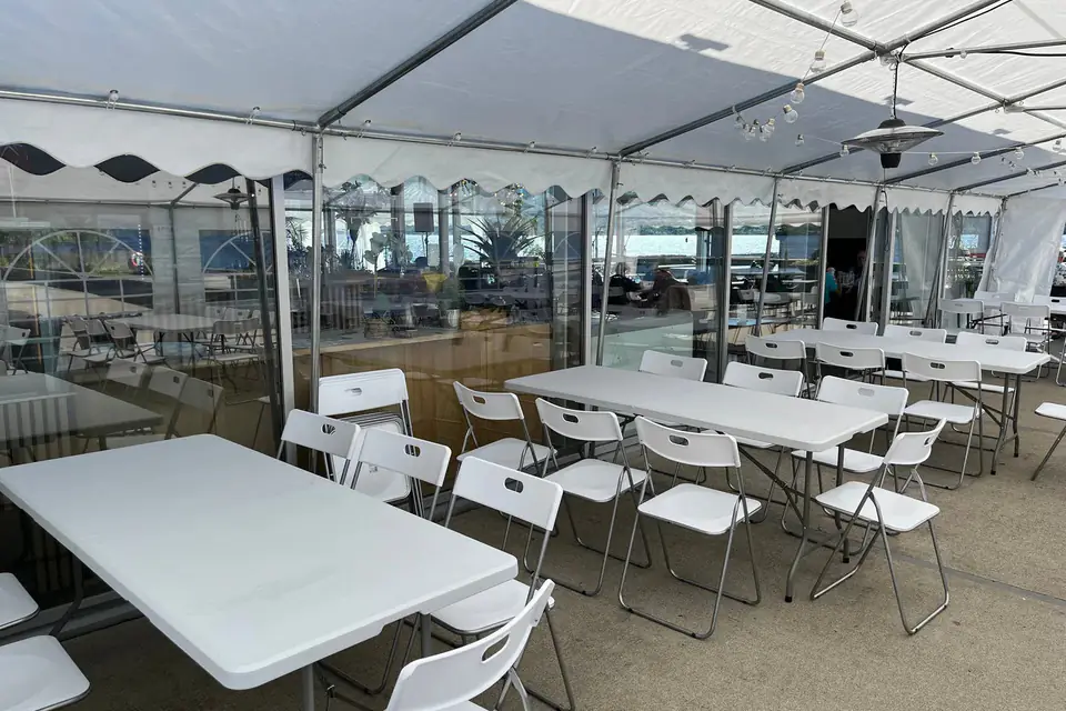 Partytelt inntil Cafe Sjøstjernen med hvite klappbord, klappstoler og varmelampe under taket