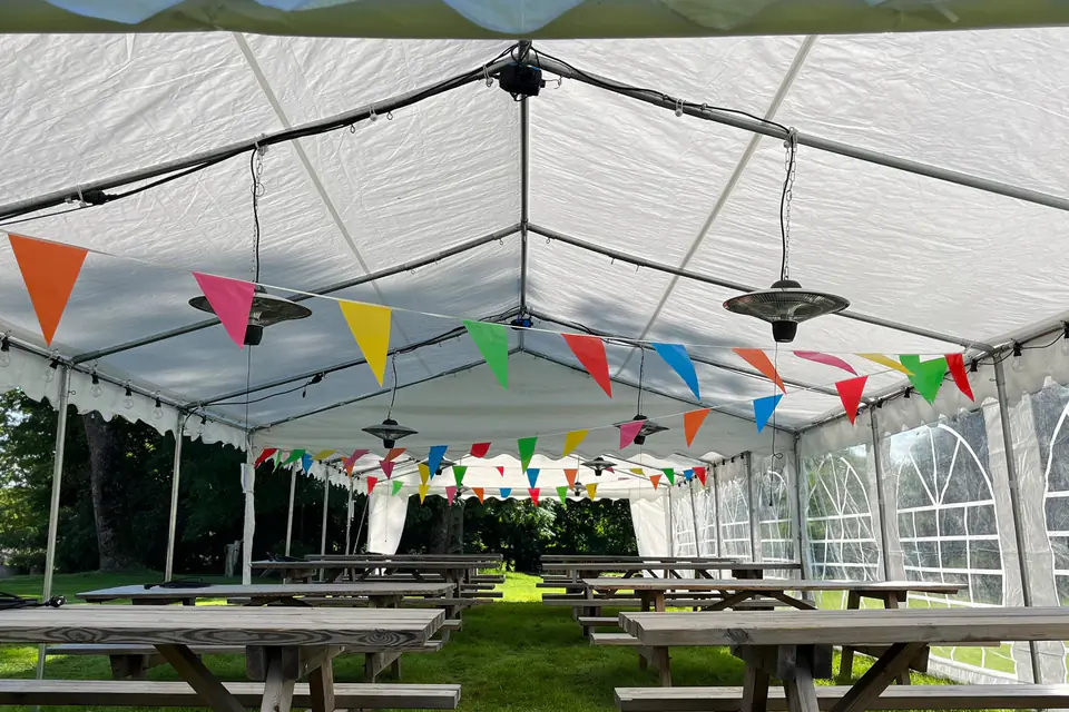 Infravarmere som henger fra taket i et langt partytelt med piknikbord og fargerike vimpler