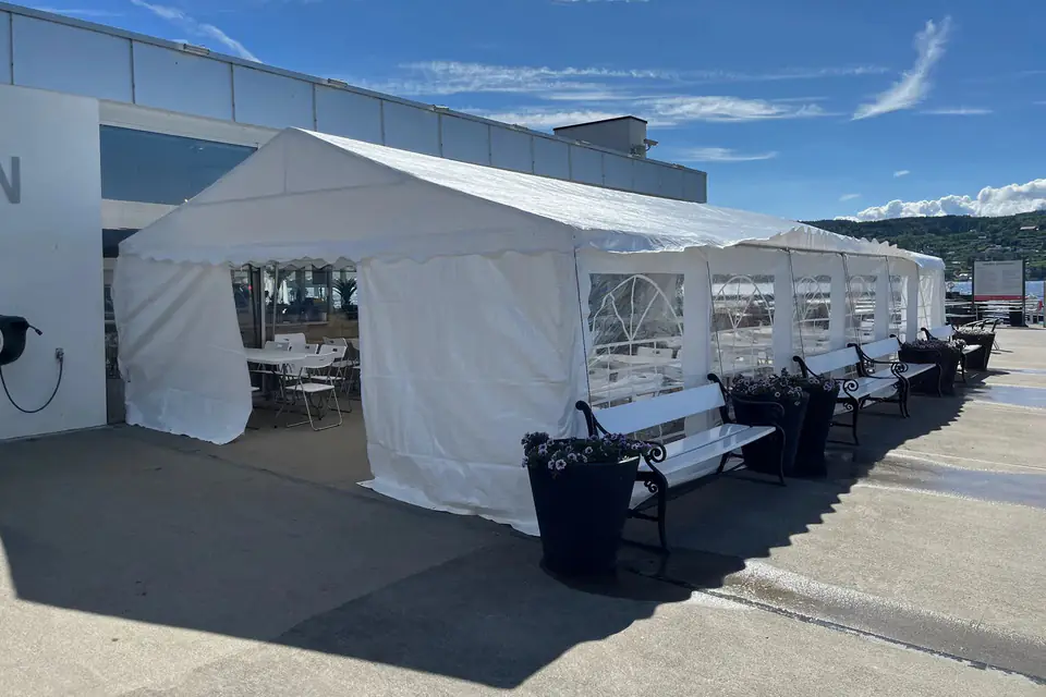Partytelt med vindusvegger satt opp som mattelt ved en kafé ved sjøen