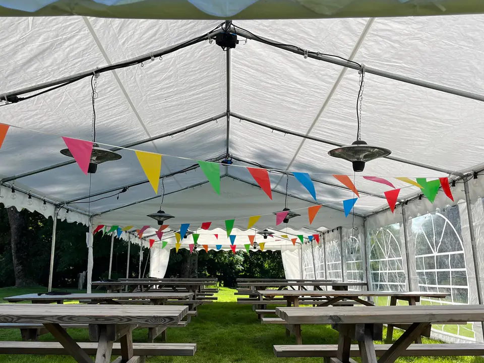 Infravarmere som henger fra taket i et langt partytelt med piknikbord og fargerike vimpler