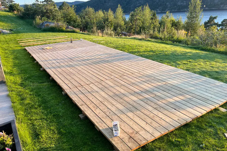 Ferdig tregulv av terrassebord på en plen, med utsikt mot fjorden